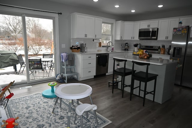 kitchen with light countertops, backsplash, stainless steel appliances, and white cabinetry