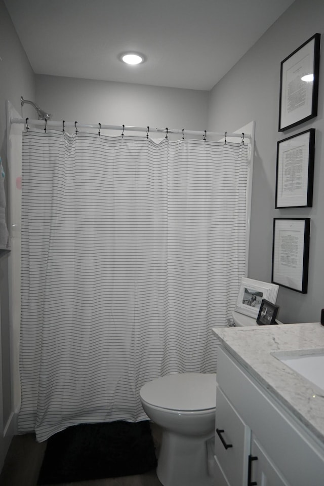 bathroom with toilet, a shower with shower curtain, and vanity