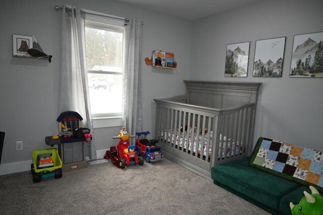 carpeted bedroom featuring baseboards and a crib