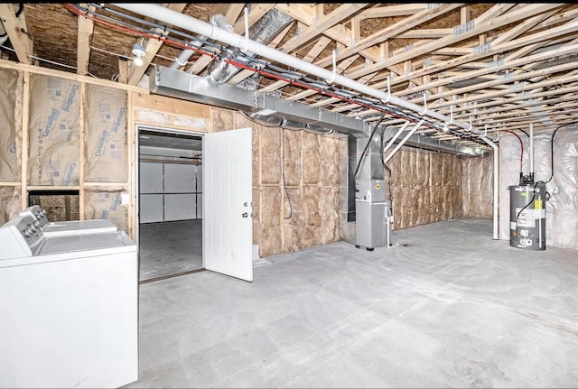 unfinished below grade area featuring water heater, heating unit, and washing machine and clothes dryer