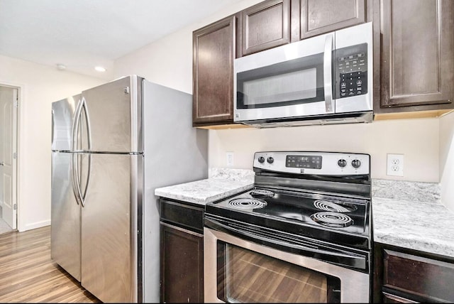 kitchen with light countertops, dark brown cabinets, appliances with stainless steel finishes, and light wood finished floors
