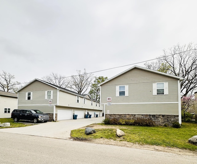 1201 Kimbark Ave, Kalamazoo, MI 49006 - view of front of home with concrete driveway, an attached garage, and a front yard