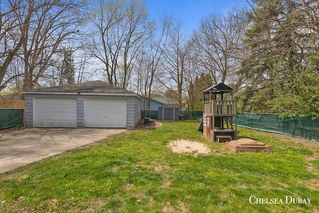 view of yard with an outbuilding, a garage, fence, a playground, and a storage unit