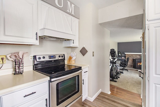 kitchen with electric range, light countertops, white cabinetry, light wood-type flooring, and custom exhaust hood