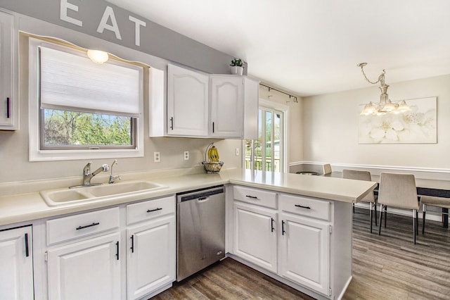 kitchen featuring a peninsula, light countertops, a sink, dishwasher, and a notable chandelier
