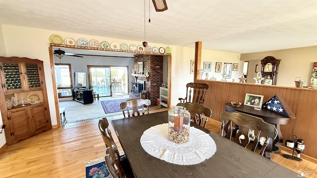 7736 S Custer Rd, Monroe, MI 48161 - dining room featuring a textured ceiling, light wood finished floors, ceiling fan, and a fireplace