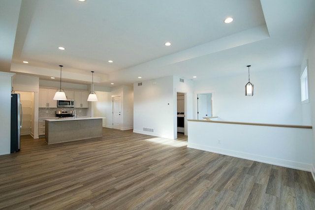 unfurnished living room featuring recessed lighting, a tray ceiling, visible vents, and dark wood-style floors