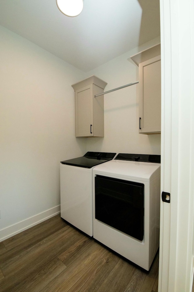 laundry room with baseboards, washing machine and dryer, cabinet space, and dark wood-type flooring