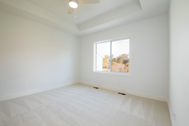 carpeted empty room featuring visible vents, baseboards, ceiling fan, and a tray ceiling