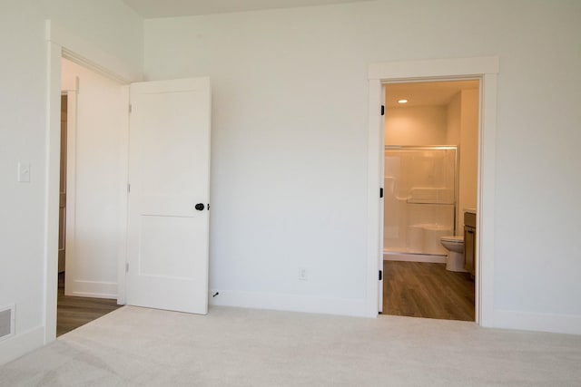 unfurnished bedroom featuring connected bathroom, baseboards, visible vents, and carpet
