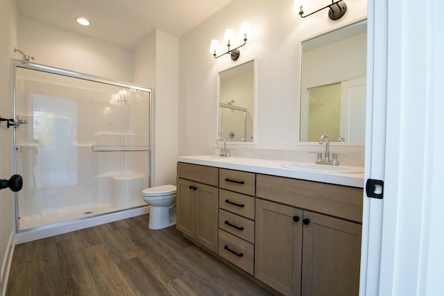 bathroom with double vanity, toilet, a sink, and a stall shower