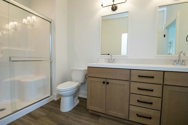 full bathroom featuring a sink, a stall shower, toilet, and wood finished floors