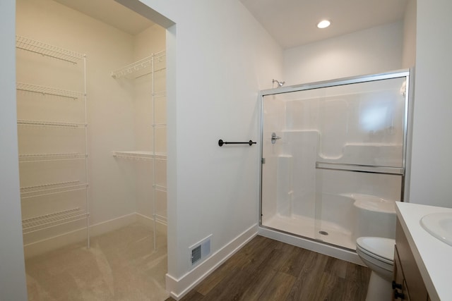bathroom with vanity, a stall shower, toilet, and visible vents