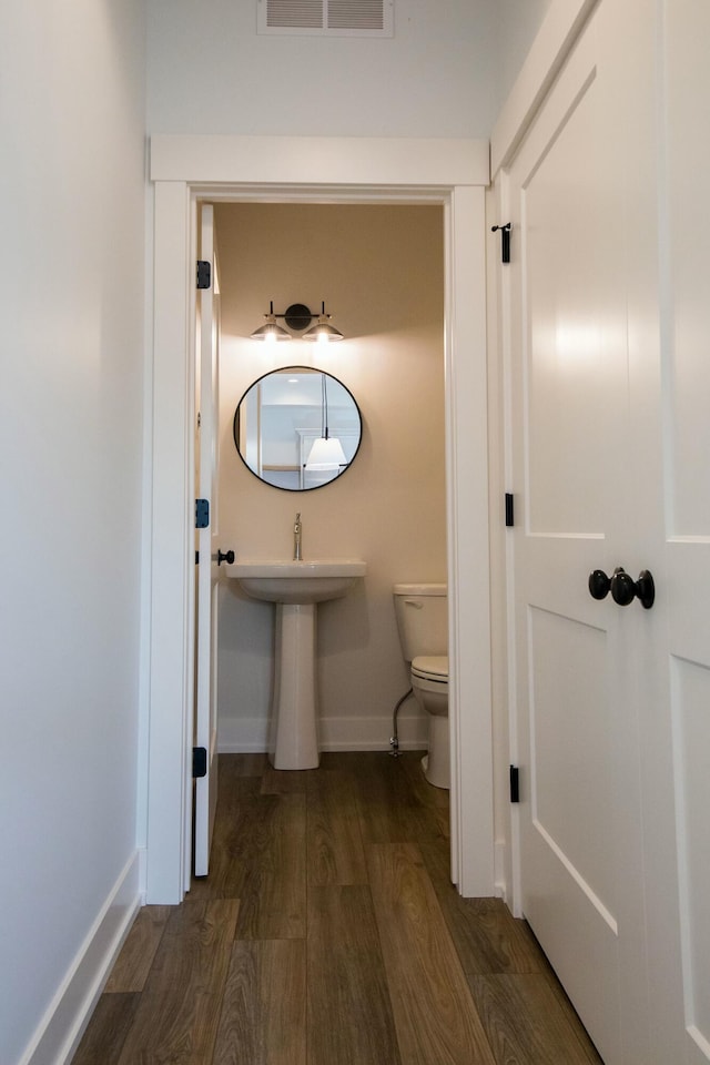 bathroom with baseboards, toilet, wood finished floors, and visible vents
