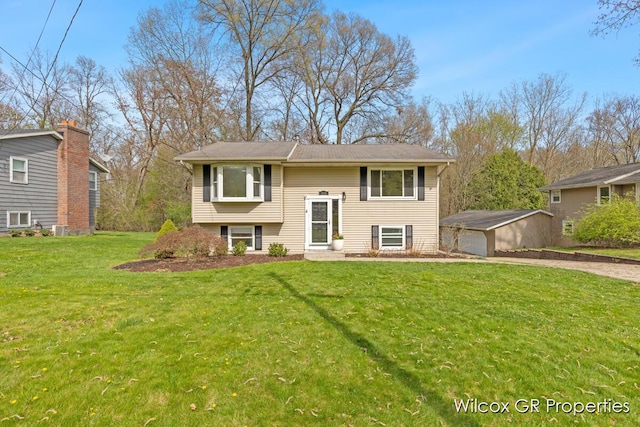 bi-level home with driveway, central air condition unit, an outbuilding, and a front yard