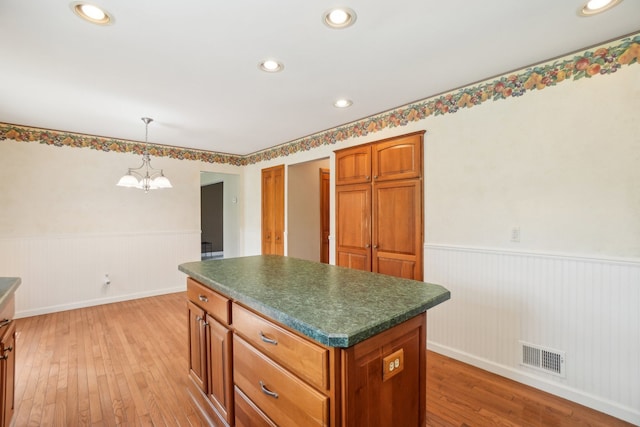 1373 Prosper Dr, Troy, MI 48098 - kitchen with wainscoting, dark countertops, a kitchen island, light wood-style flooring, and a chandelier