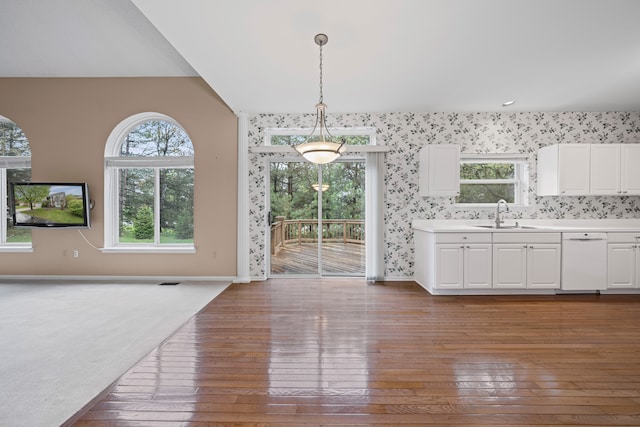 unfurnished dining area with baseboards, a sink, and hardwood / wood-style flooring
