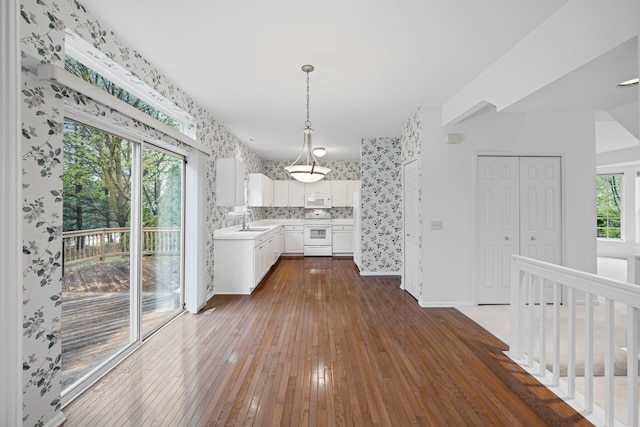 kitchen with a sink, white cabinets, dark wood-style flooring, white appliances, and light countertops