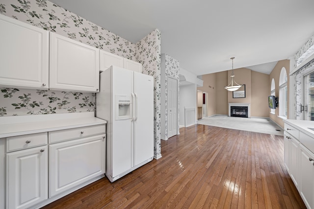 kitchen with hardwood / wood-style floors, open floor plan, white refrigerator with ice dispenser, and wallpapered walls