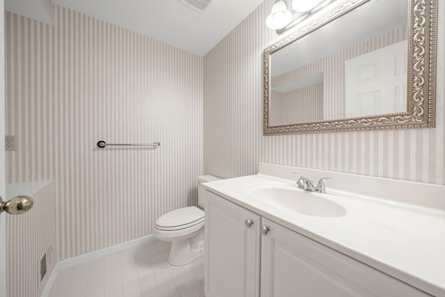 bathroom featuring toilet, wallpapered walls, baseboards, tile patterned flooring, and vanity