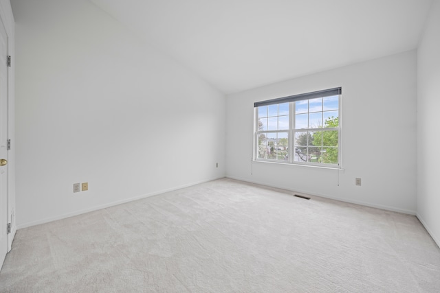 carpeted empty room featuring vaulted ceiling, baseboards, and visible vents