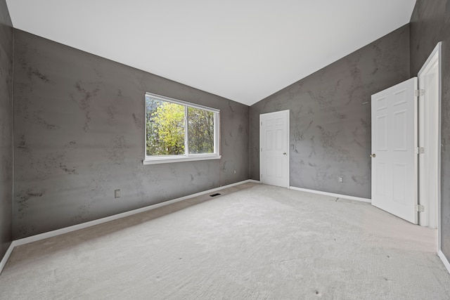 unfurnished bedroom featuring vaulted ceiling, carpet flooring, baseboards, and visible vents