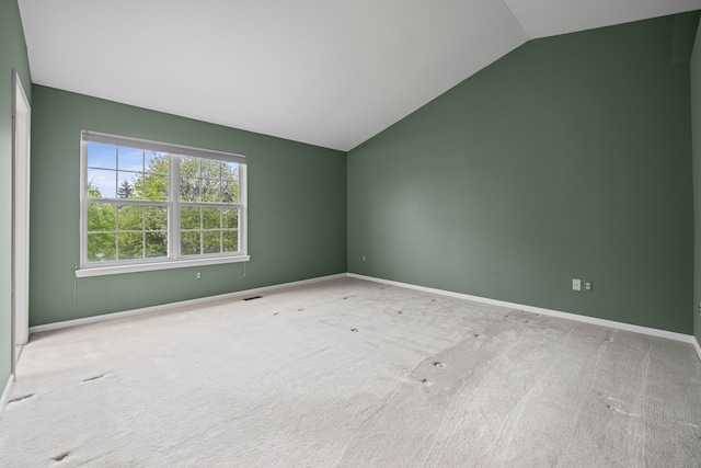 spare room featuring carpet, vaulted ceiling, and baseboards