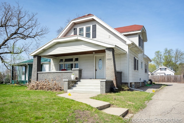 bungalow-style home with fence, covered porch, and a front yard