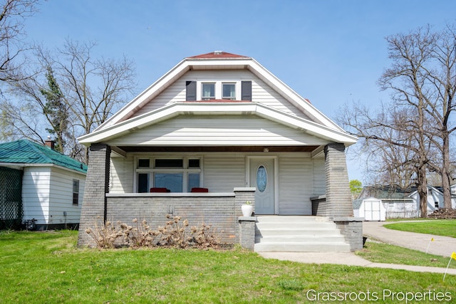 bungalow-style house with a porch, a front lawn, a shed, and an outbuilding