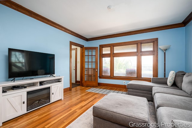 living room with baseboards, ornamental molding, and light wood-type flooring