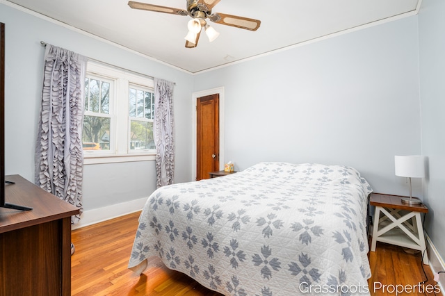 bedroom featuring crown molding, baseboards, and wood finished floors