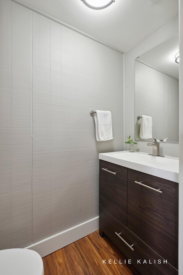 bathroom featuring toilet, baseboards, wood finished floors, and vanity