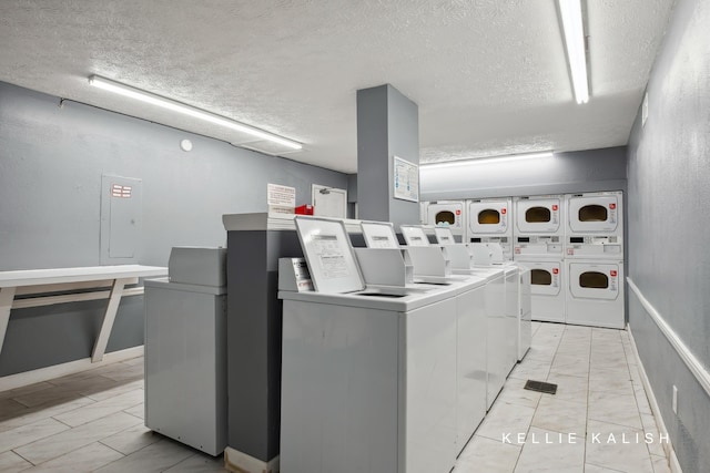 shared laundry area with stacked washer and dryer, marble finish floor, a textured ceiling, and washing machine and clothes dryer