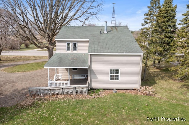 back of property featuring a yard and a shingled roof