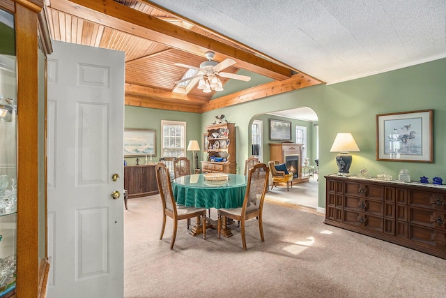 3500 N Oceana Dr, Hart, MI 49420 - dining space with carpet floors, a ceiling fan, beam ceiling, a lit fireplace, and arched walkways
