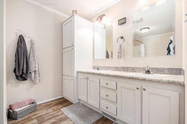 full bath with ornamental molding, a sink, and wood finished floors