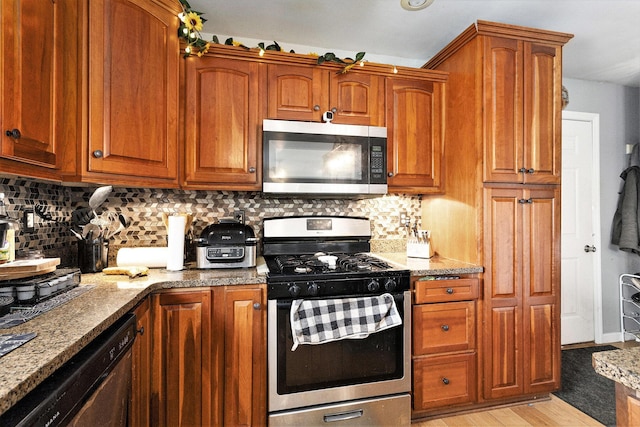 kitchen featuring light wood-style floors, appliances with stainless steel finishes, light stone counters, and tasteful backsplash