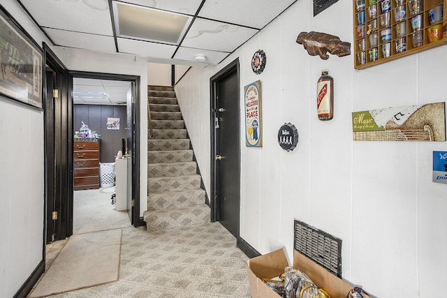 hallway with carpet floors, a paneled ceiling, and stairway