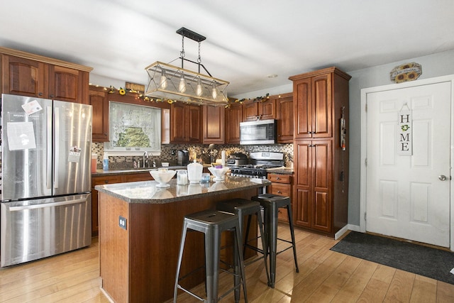 kitchen with a breakfast bar area, a kitchen island, backsplash, stainless steel appliances, and light wood-style flooring