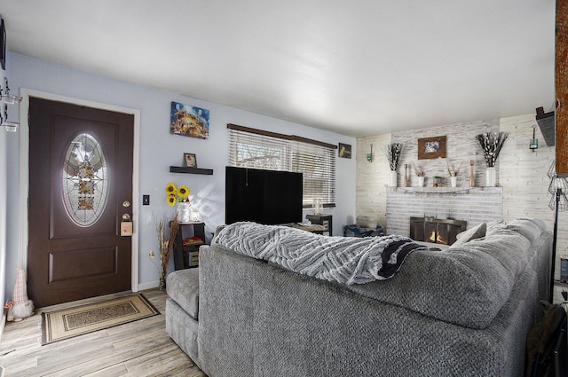 living area with light wood-style floors, baseboards, a wealth of natural light, and a fireplace