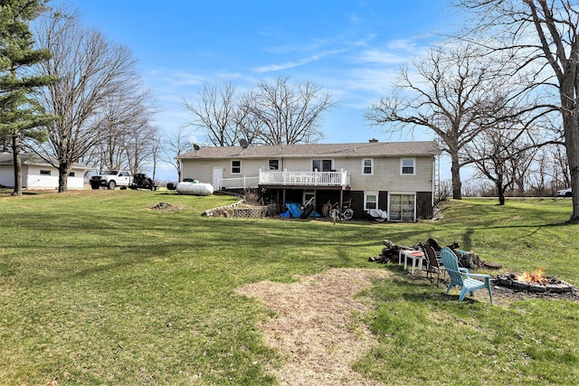 back of property featuring a lawn, a chimney, a wooden deck, and an outdoor fire pit