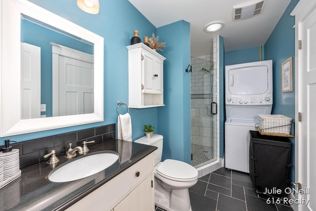 full bathroom featuring visible vents, vanity, toilet, stacked washing maching and dryer, and a stall shower