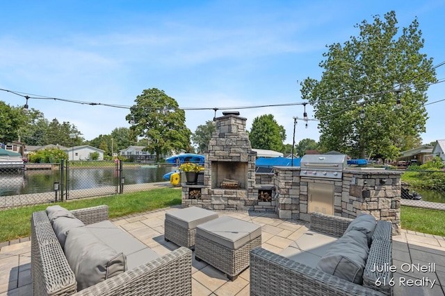 view of patio / terrace with fence, an outdoor living space with a fireplace, exterior kitchen, grilling area, and a gate