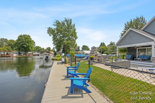 view of dock with fence, an outdoor hangout area, a patio area, a water view, and a yard