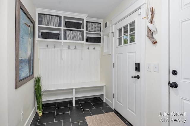 mudroom with dark tile patterned flooring and baseboards