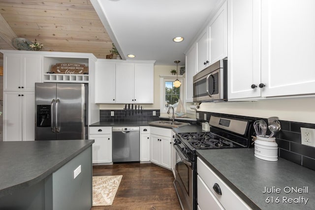 kitchen featuring stainless steel appliances, dark countertops, a sink, and open shelves