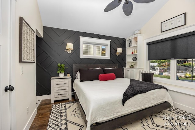 bedroom featuring baseboards, an accent wall, multiple windows, and dark wood-style floors