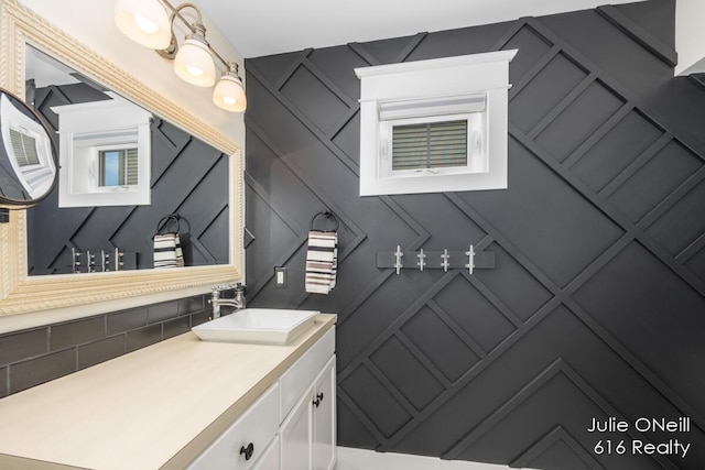 bathroom with backsplash, vanity, and a decorative wall