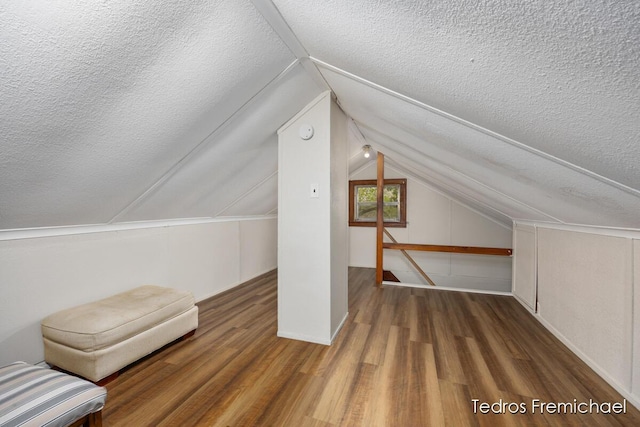 bonus room with baseboards, vaulted ceiling, a textured ceiling, and wood finished floors