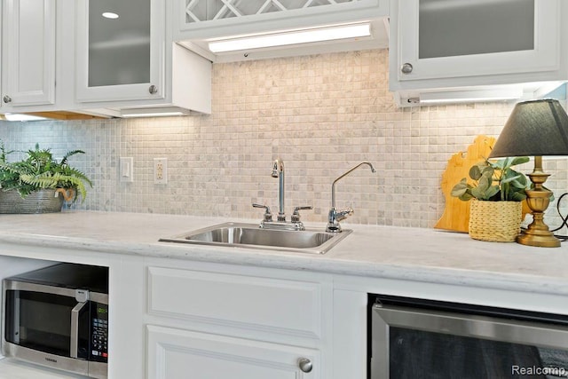 1319 Rochester Rd, Leonard, MI 48367 - kitchen with beverage cooler, stainless steel microwave, a sink, white cabinetry, and glass insert cabinets